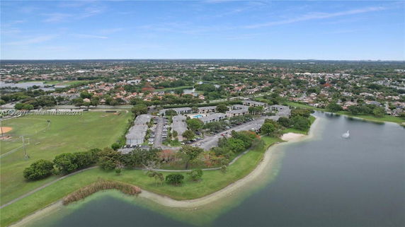 Aerial view of a residential complex by a lake, with surrounding park and houses.