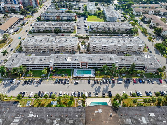 Aerial view of multiple residential buildings with parking areas and swimming pools.