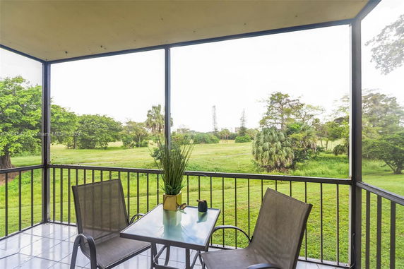 Open balcony with patio table and chairs overlooking a grassy landscape.