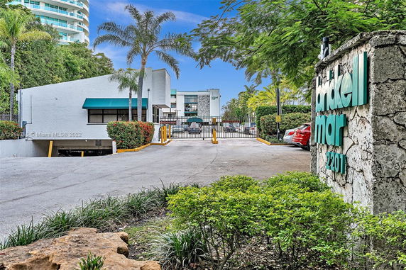 Front view of a building with a gated entrance and parking area.