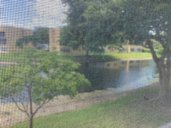 View of buildings and pond through a mesh screen from inside.