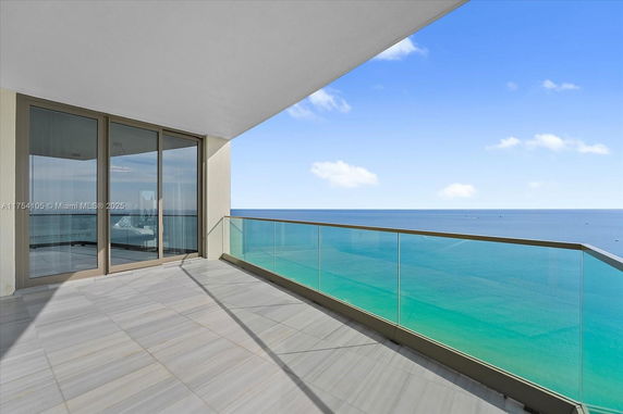 Balcony with glass railing and ocean view.