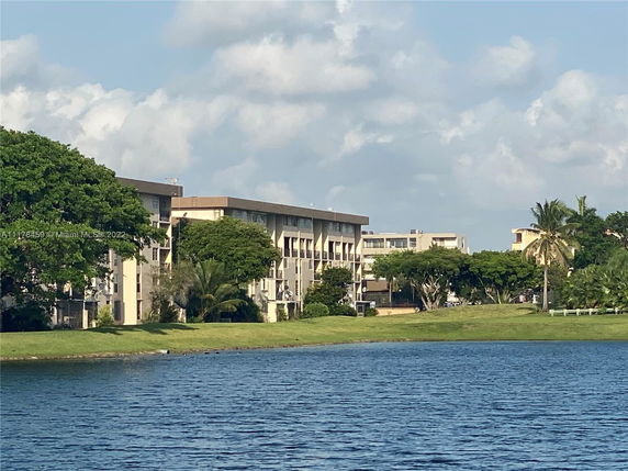 View of buildings near a body of water with surrounding greenery.