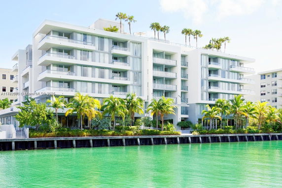 Front view of a multi-story modern apartment building by a waterway.
