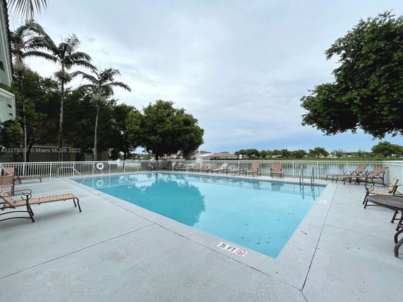 Outdoor swimming pool area with lounge chairs and surrounding greenery.