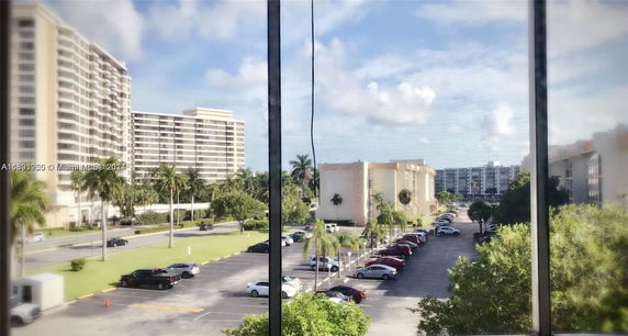 View of apartment buildings and parking lot from a window.