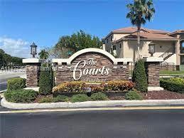 Front view of a residential entrance with a sign 'The Courts' and stone columns.