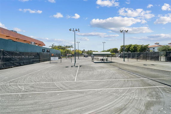 A tennis court with multiple nets, surrounded by fencing and lighting poles.