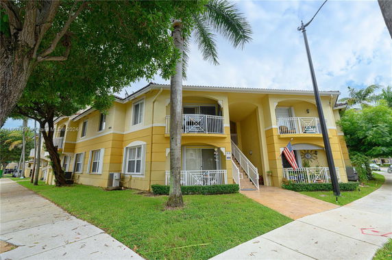 Front view of a two-story residential building with balconies and stairs.