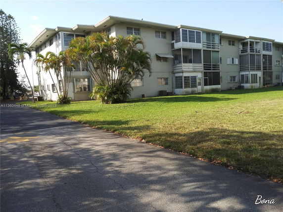 Front view of a three-story residential building with multiple windows and balconies.