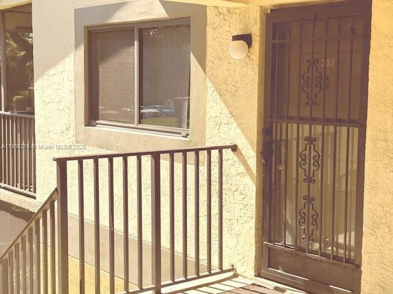 Exterior view of a building entrance with metal railing and security door.