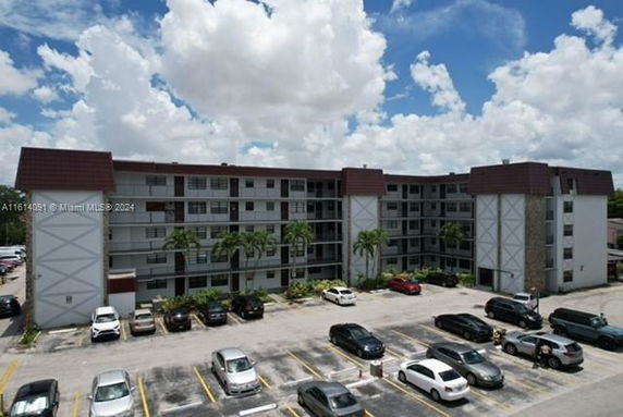 Front view of a multi-story residential building with parking area.