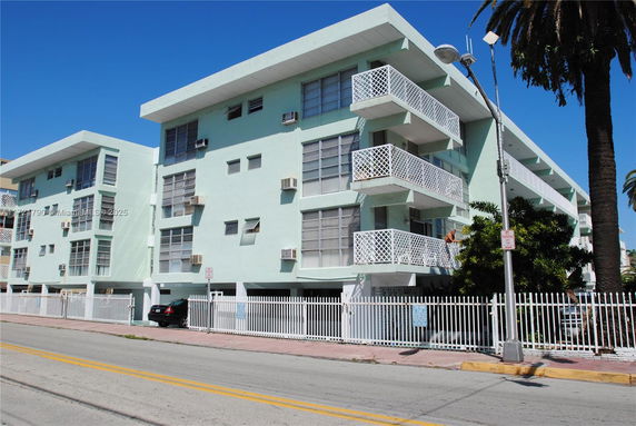Front view of a multi-story building with balconies and a gated entrance.