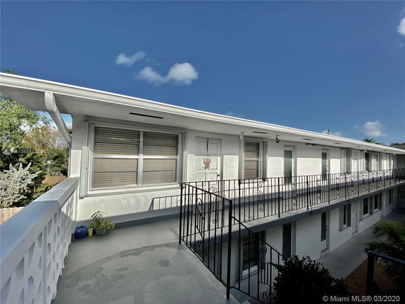 Front view of a two-story building with balcony and railing.