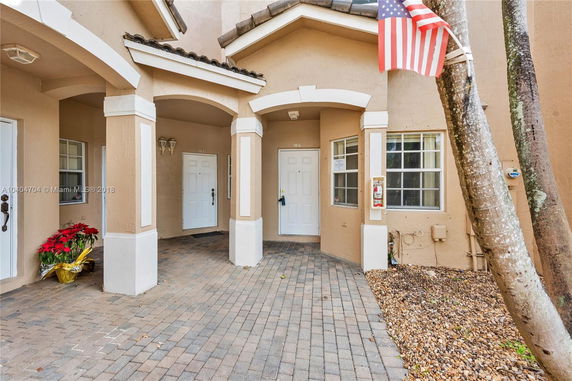 Front view of a multi-unit residential building with arched entryways and white doors.