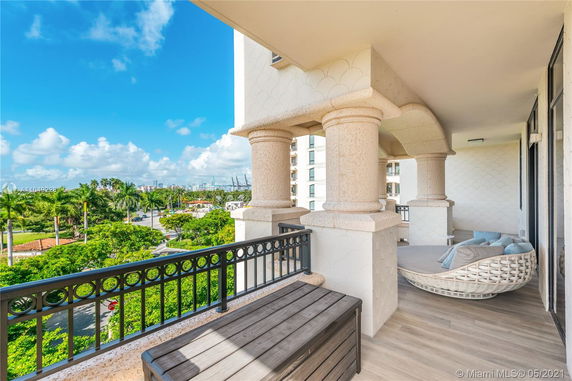 Panoramic view from a balcony with stone columns, overlooking a lush green area and city skyline in the distance.