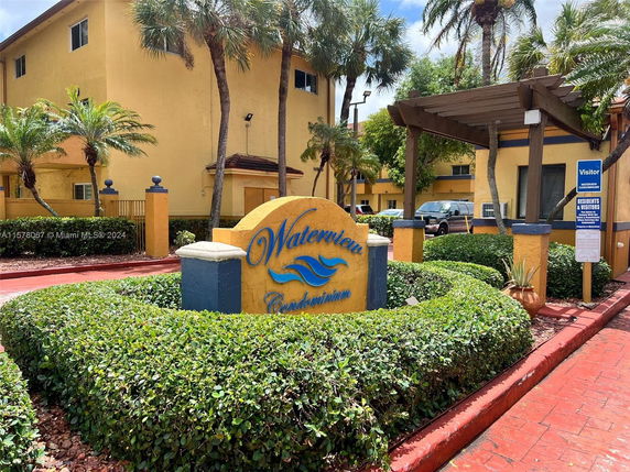 Front view of a condominium complex with a sign reading 'Waterview Condominiums' and landscaped shrubbery.