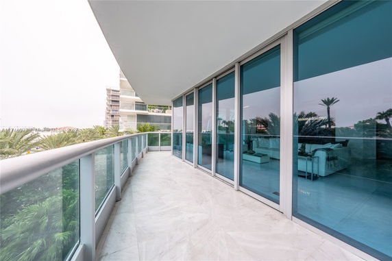 Balcony view of a building with glass railing and floor-to-ceiling windows.