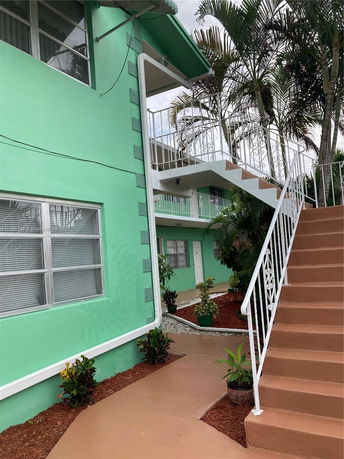 Front view of a two-story building with green exterior and white railings.