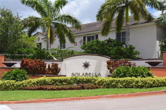 Front view of a house with a landscaped entrance and palm trees.