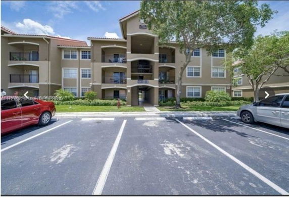 Front view of a three-story apartment building with balconies and parking area.