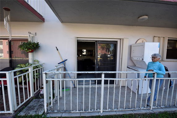 Front view of a building entrance with a small fenced-in patio area.
