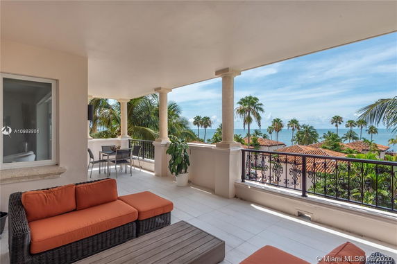Balcony view overlooking a scenic coastal area with palm trees and ocean.