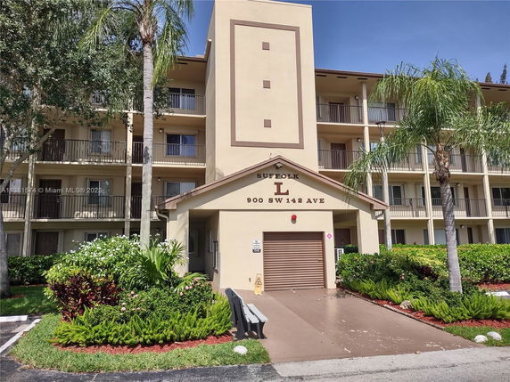 Front view of a multi-story apartment building with balconies and a central entrance.