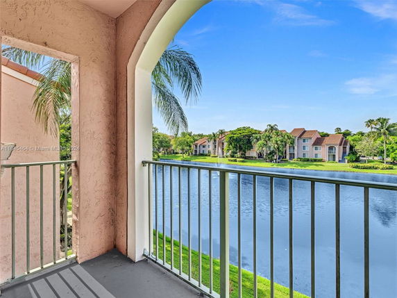 View from a building balcony overlooking a lake with surrounding houses and trees.