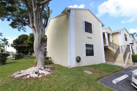 Front view of a two-story residential building with stairs leading to the entrance.