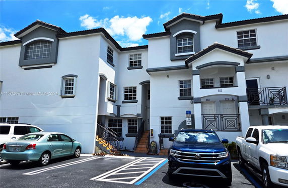 Front view of a multi-story residential building with parking area.