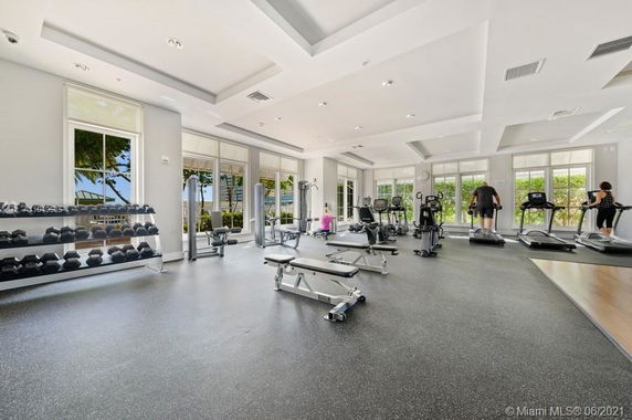 Interior view of a gym with exercise equipment and large windows.