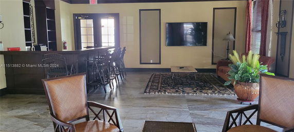 Recreational room with a bar counter, chairs, and a wall-mounted TV.