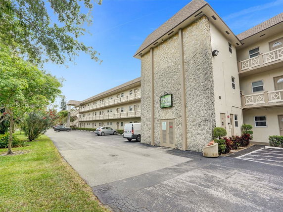 Front view of a multi-story residential building with parking spaces.