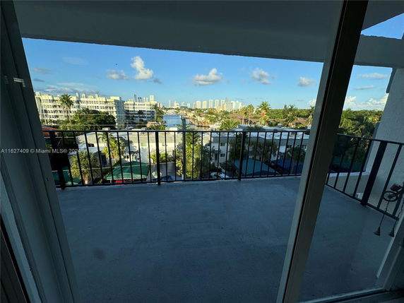 View from a balcony overlooking a cityscape with buildings and greenery.