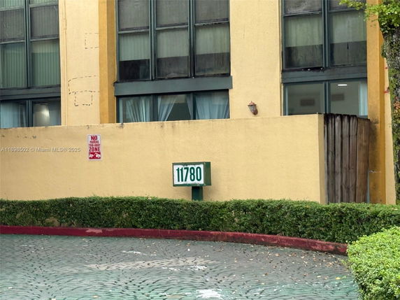Front view of a multi-story building with large windows and a fence.