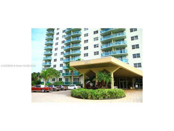Front view of a multi-story residential building with balconies and an entrance canopy.