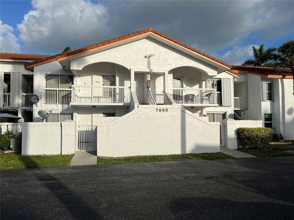Front view of a two-story residential building with balconies and orange-tiled roof.