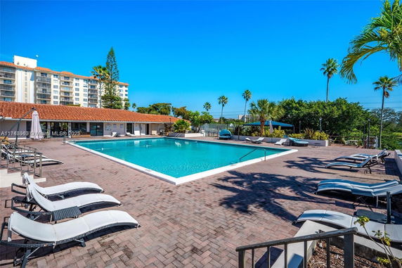 Outdoor swimming pool area with lounge chairs and surrounding greenery.