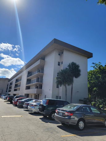 Front view of a multi-story residential building with parking area.