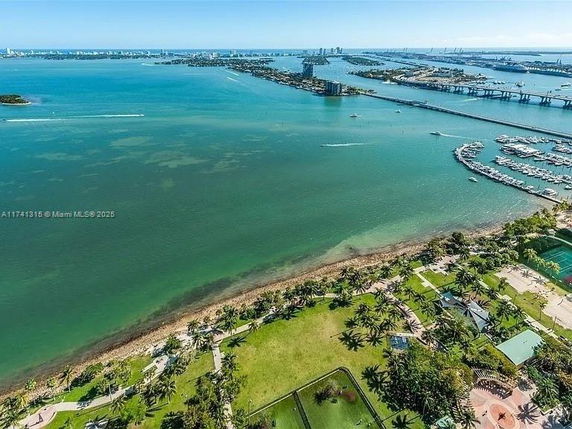 Aerial view of a coastal landscape with a beach, palm trees, and a marina.