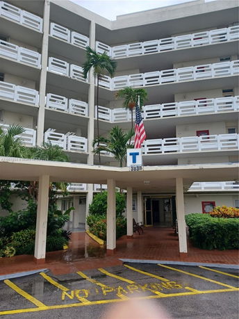 Front view of a multi-story building with balconies and a covered entrance.