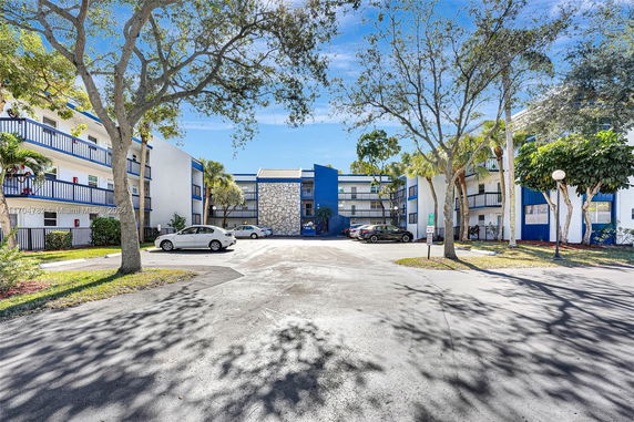 Outdoor parking area in front of a multi-story apartment building with blue accents.