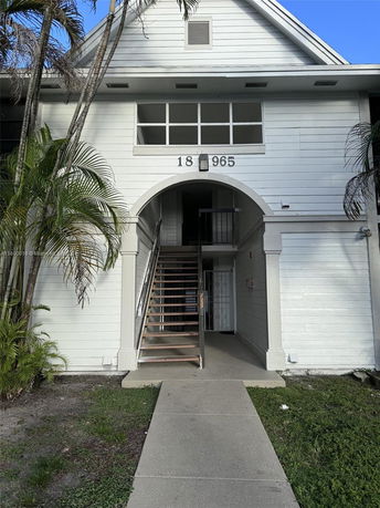 Front view of a two-story building with an arched entrance and exterior staircase.