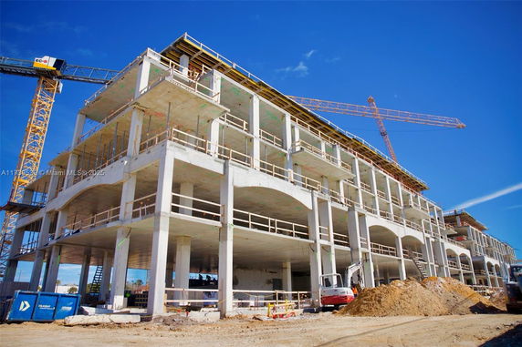 Front view of a multi-story building under construction with cranes.