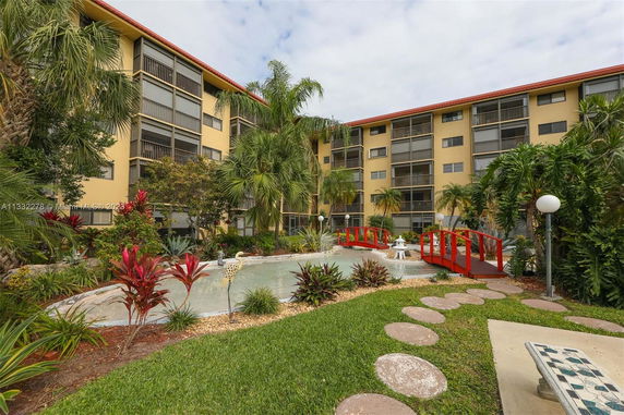 Exterior view of a multi-story building with screened balconies and landscaped garden.