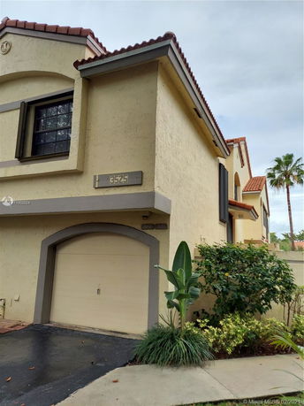 Front view of a two-story house with a garage and arched roof design.