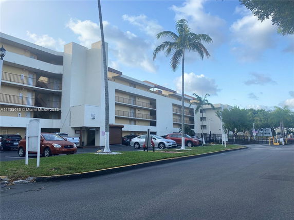 Front view of a multi-story apartment building with parking space.