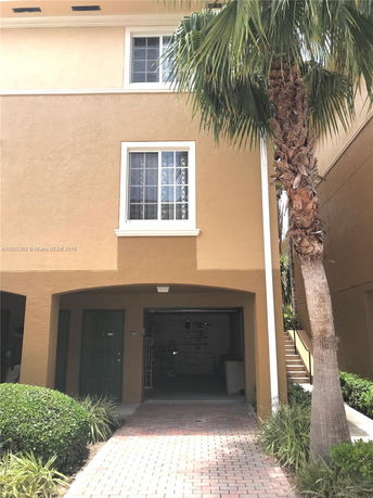 Front view of a multi-story house with a garage entrance beneath and two windows on upper floors.