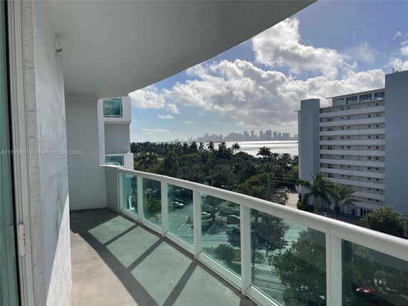 View of surrounding areas from a building balcony with a city skyline and water body in the distance.